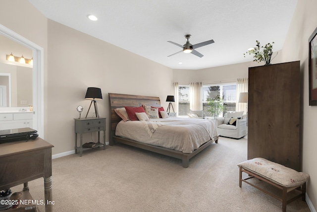 bedroom with ceiling fan, connected bathroom, and light carpet