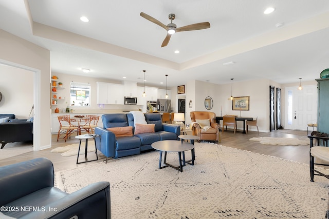 living room with wood-type flooring, ceiling fan, and a tray ceiling