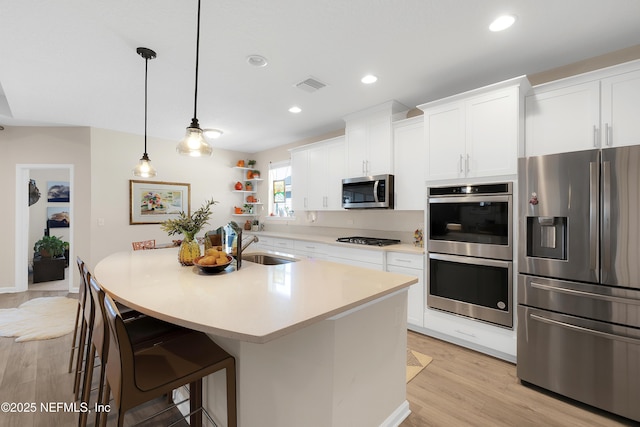 kitchen with white cabinetry, stainless steel appliances, a kitchen breakfast bar, and pendant lighting