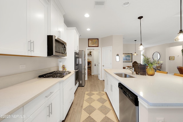 kitchen featuring sink, decorative light fixtures, white cabinets, and appliances with stainless steel finishes