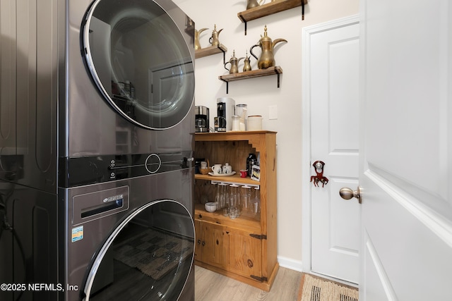 clothes washing area featuring stacked washer / drying machine and light wood-type flooring