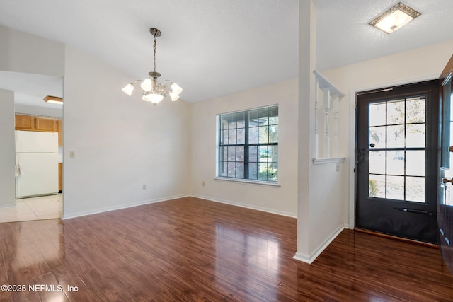 entrance foyer with a notable chandelier, wood-type flooring, vaulted ceiling, and a healthy amount of sunlight