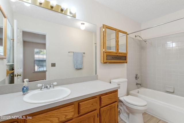 full bathroom featuring vanity, tiled shower / bath, toilet, and a textured ceiling