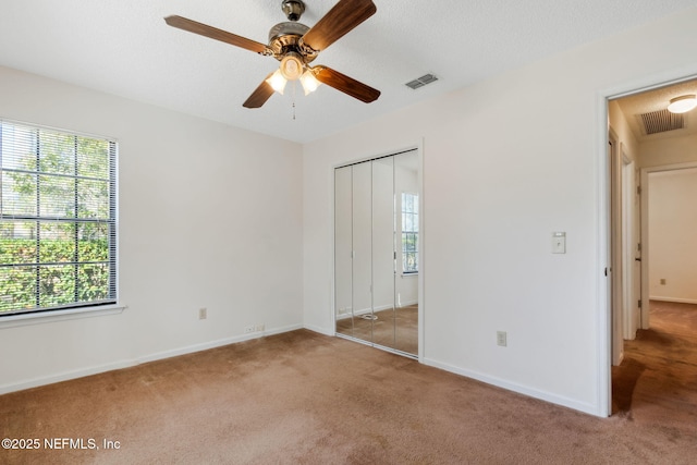 unfurnished bedroom with ceiling fan, carpet floors, a textured ceiling, and a closet