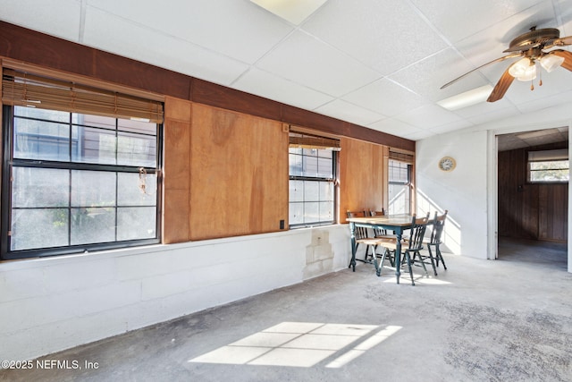 unfurnished dining area with a drop ceiling, concrete floors, and ceiling fan