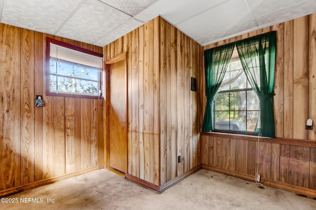 interior space with plenty of natural light, concrete floors, and wood walls