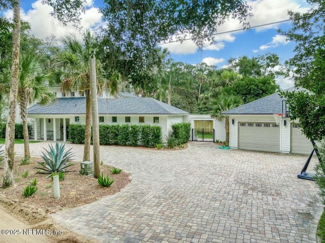 ranch-style house featuring a garage, decorative driveway, and roof with shingles