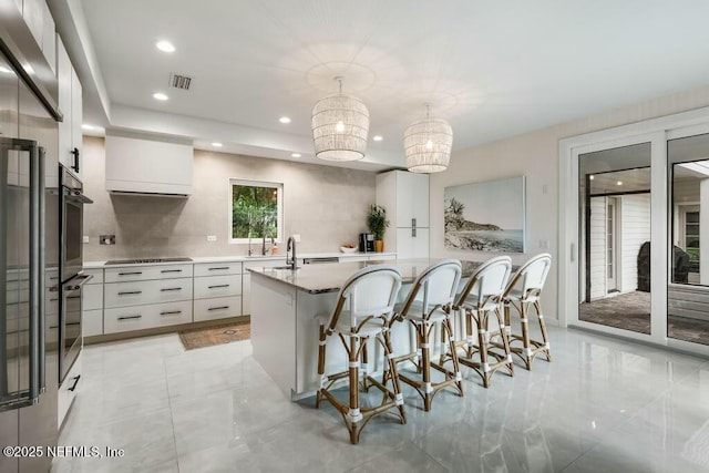 kitchen featuring hanging light fixtures, modern cabinets, white cabinets, and a center island with sink