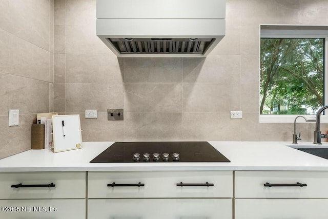 kitchen featuring white cabinets, light countertops, premium range hood, and black electric cooktop