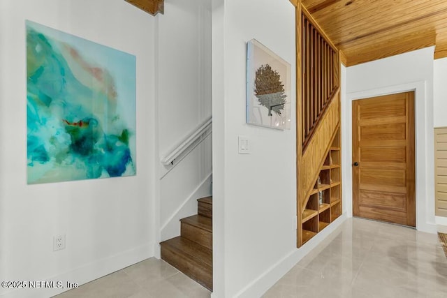 staircase featuring tile patterned flooring, wood ceiling, and baseboards