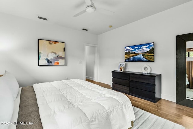 bedroom featuring a ceiling fan, baseboards, visible vents, and wood finished floors