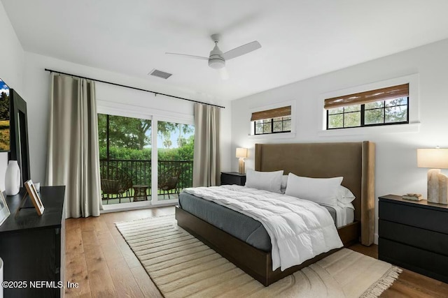 bedroom featuring access to exterior, wood finished floors, visible vents, and multiple windows