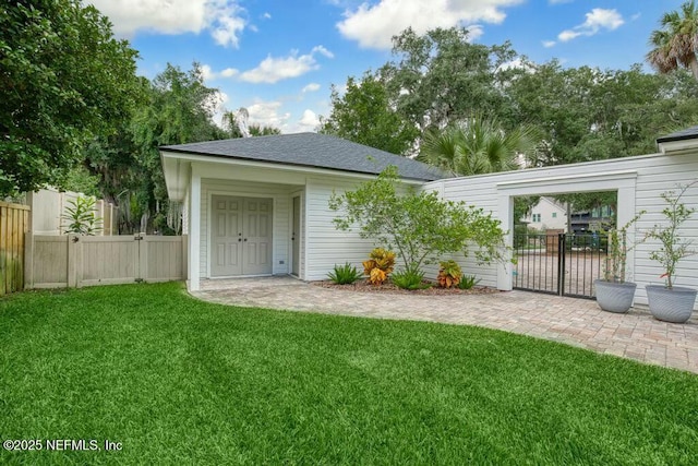 rear view of house featuring a yard, a shingled roof, and fence