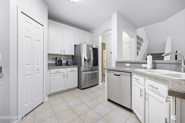 kitchen with white cabinetry, sink, light tile patterned floors, and stainless steel appliances