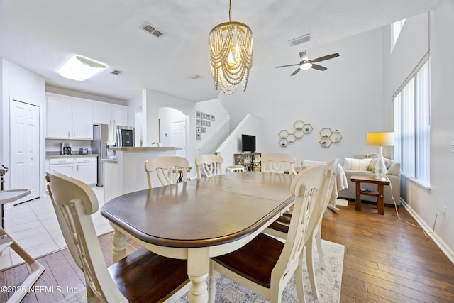 dining space featuring ceiling fan with notable chandelier, light hardwood / wood-style flooring, and a textured ceiling