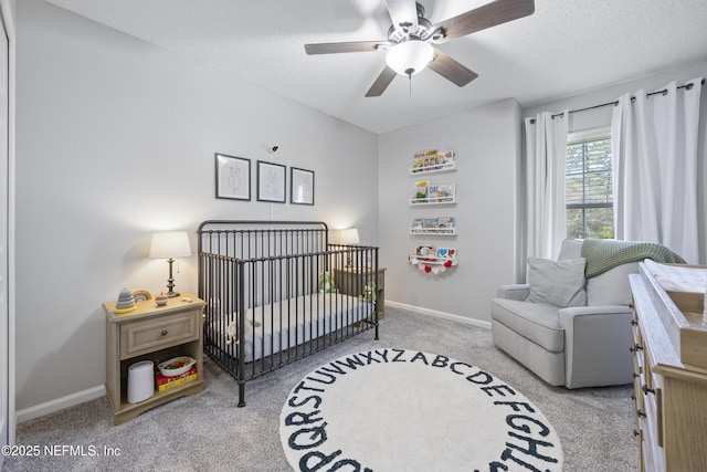 carpeted bedroom with ceiling fan, a crib, and a textured ceiling