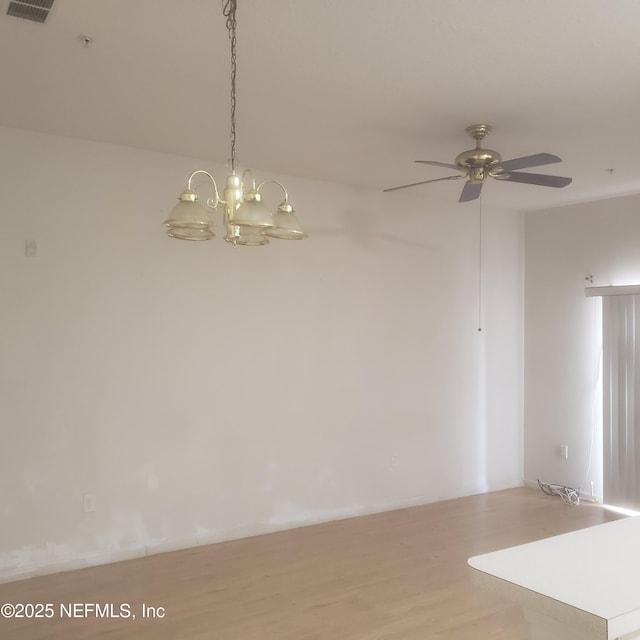 empty room with wood finished floors and ceiling fan with notable chandelier