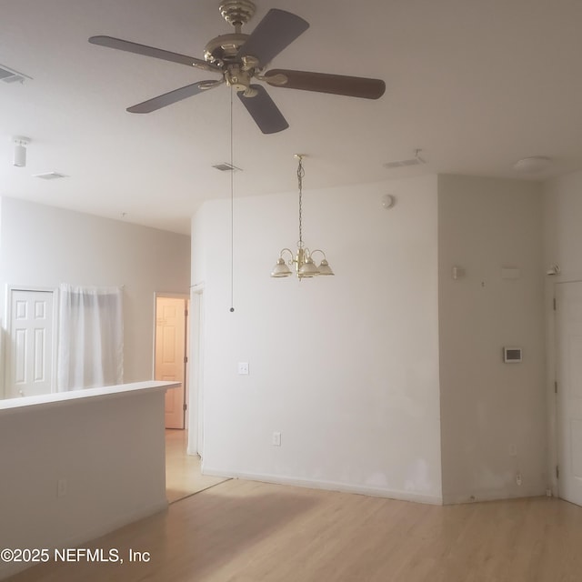 empty room featuring visible vents, light wood finished floors, and ceiling fan with notable chandelier