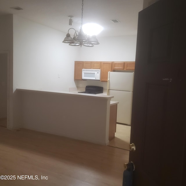 kitchen with a chandelier, white appliances, light wood finished floors, and visible vents