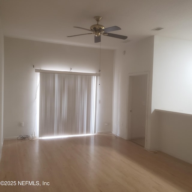 empty room with a ceiling fan, visible vents, and wood finished floors