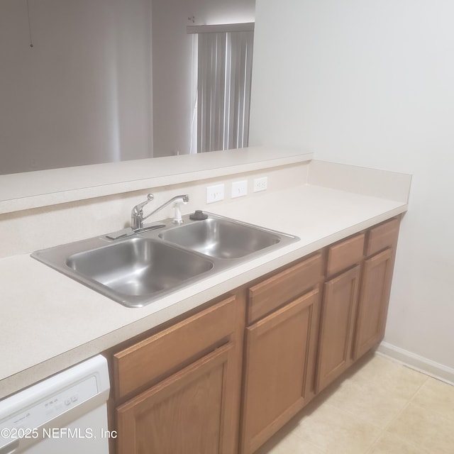 kitchen with brown cabinets, white dishwasher, light countertops, and a sink