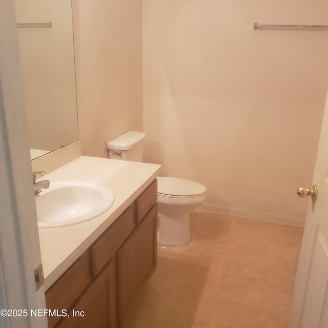 half bathroom with tile patterned flooring, vanity, toilet, and baseboards