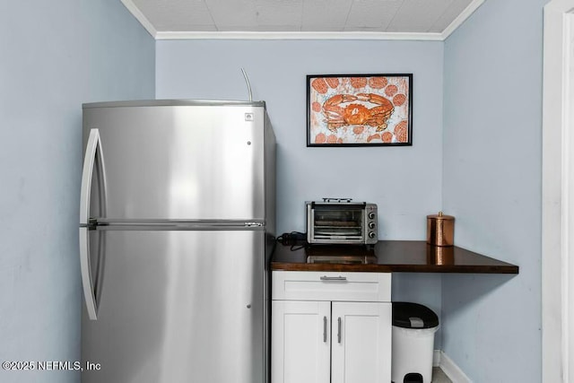 kitchen with crown molding, stainless steel fridge, and white cabinets