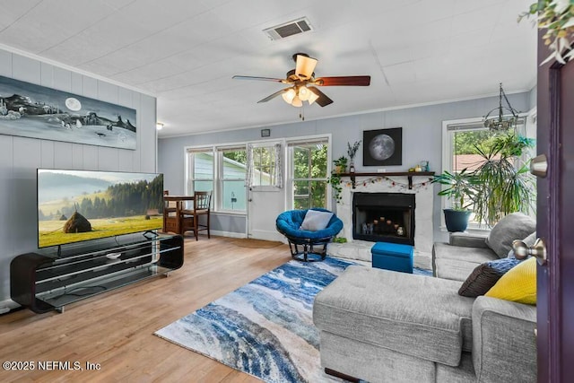 living room featuring crown molding, ceiling fan, a high end fireplace, and wood-type flooring