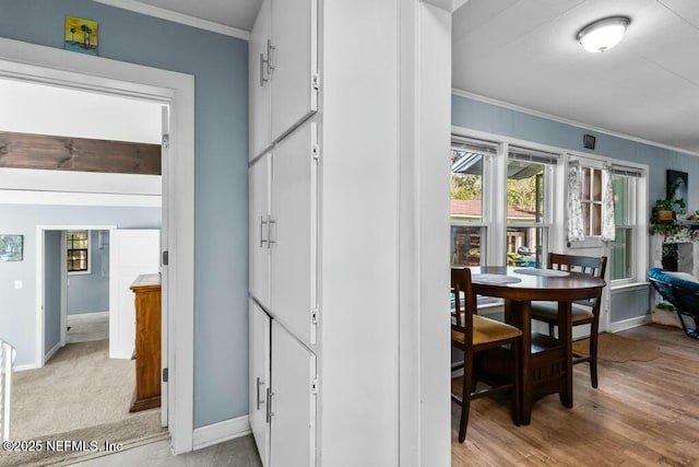 hall with ornamental molding and light hardwood / wood-style floors