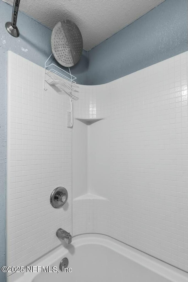 bathroom with tiled shower / bath and a textured ceiling