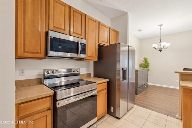 kitchen with an inviting chandelier, hanging light fixtures, stainless steel appliances, and light tile patterned flooring