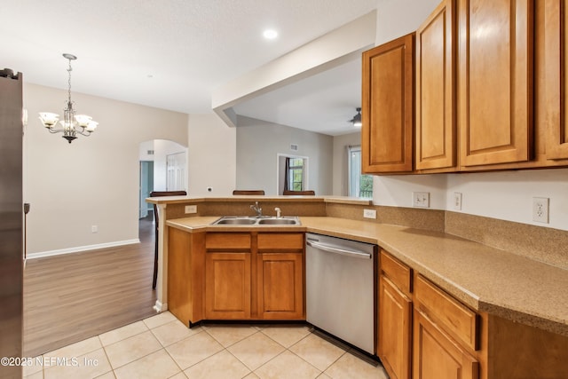 kitchen with light tile patterned flooring, dishwasher, sink, hanging light fixtures, and kitchen peninsula