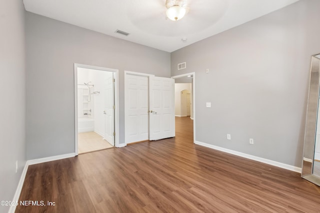 unfurnished bedroom featuring ceiling fan, connected bathroom, and hardwood / wood-style floors