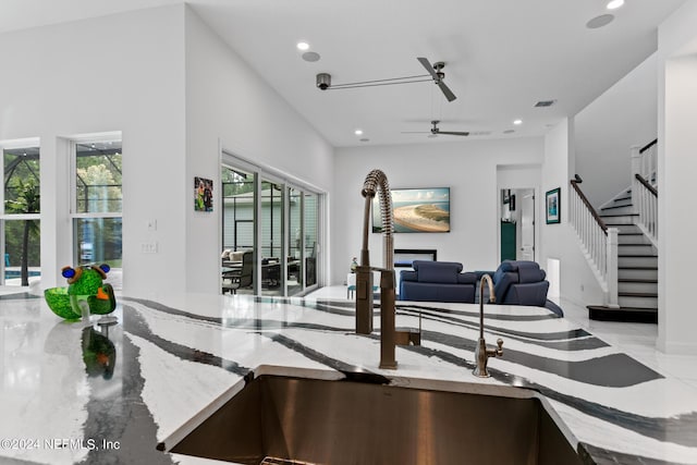 interior space with light stone counters, sink, and ceiling fan