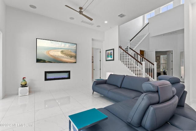 living room with ceiling fan and a high ceiling