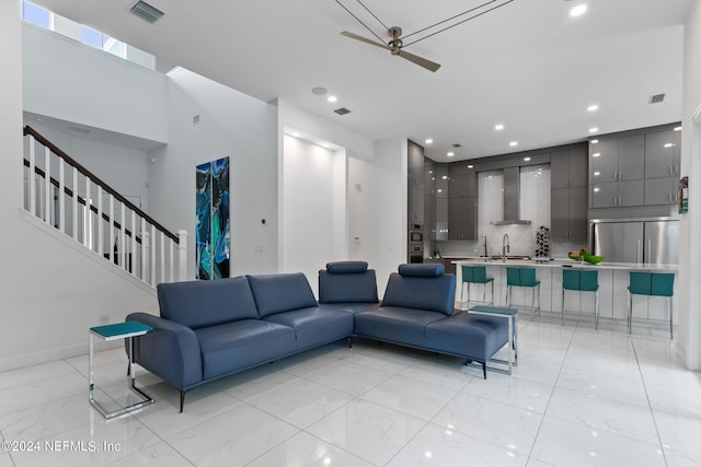 living room featuring sink, ceiling fan, and a towering ceiling