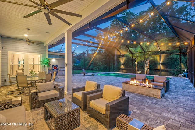 view of patio / terrace with ceiling fan, glass enclosure, and an outdoor living space with a fire pit