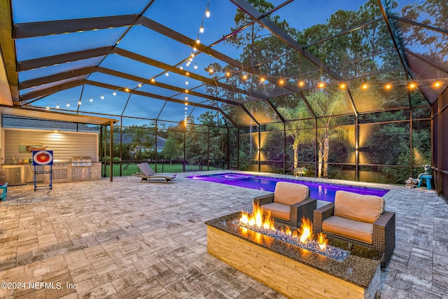 patio terrace at dusk with an outdoor kitchen, an outdoor fire pit, and glass enclosure