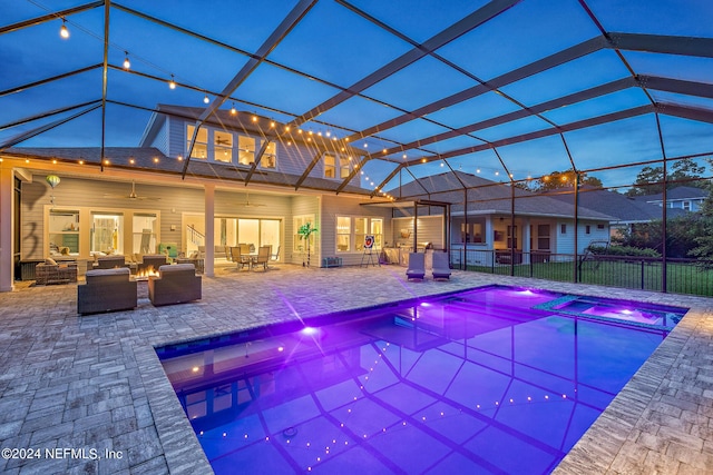 view of pool featuring ceiling fan, glass enclosure, a patio area, an outdoor living space with a fire pit, and an in ground hot tub