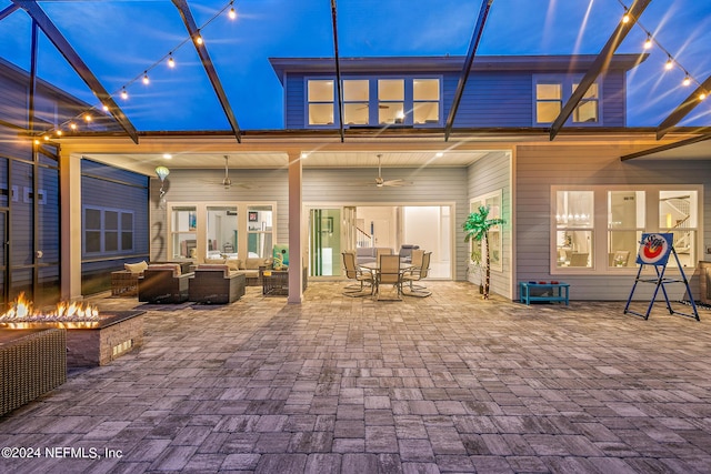 back house at dusk with an outdoor living space with a fire pit, a patio, and ceiling fan