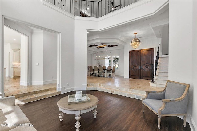 foyer with hardwood / wood-style flooring, a towering ceiling, and a chandelier