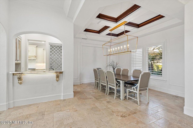 dining space with coffered ceiling, crown molding, a chandelier, and a towering ceiling