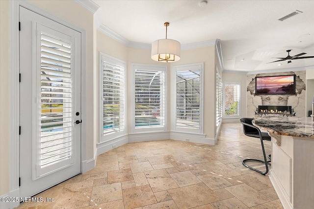 dining room featuring crown molding, ceiling fan, and a fireplace