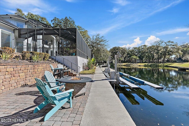 view of patio / terrace with a fire pit, a water view, a boat dock, and glass enclosure