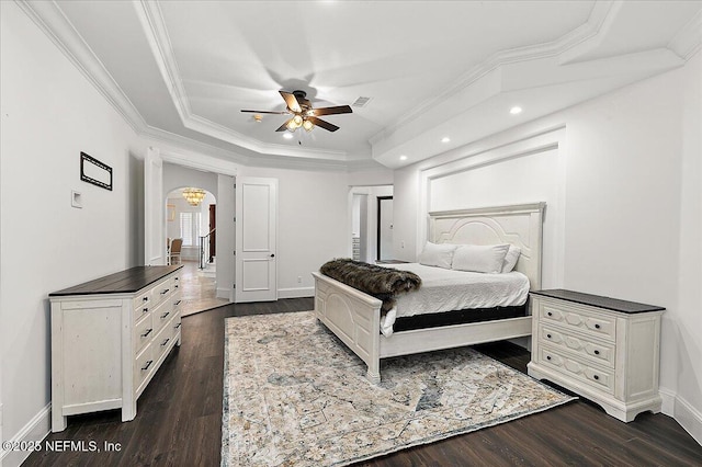 bedroom with crown molding, dark hardwood / wood-style floors, and a tray ceiling