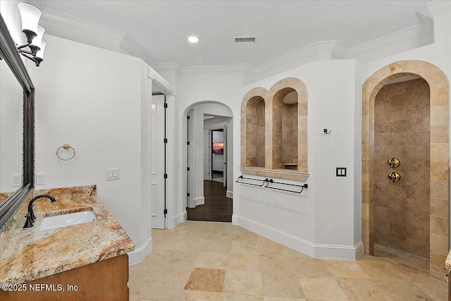 bathroom featuring crown molding, tiled shower, and vanity