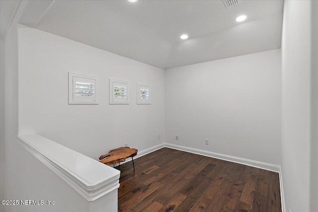 spare room featuring vaulted ceiling and dark hardwood / wood-style floors