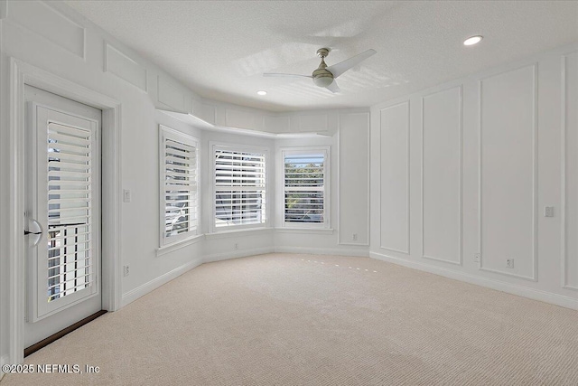 unfurnished room with ceiling fan, light colored carpet, and a textured ceiling