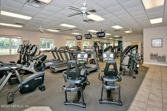 workout area with a drop ceiling, light tile patterned floors, and ceiling fan