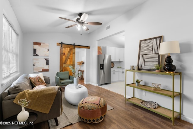 living room featuring light hardwood / wood-style floors, a barn door, and ceiling fan